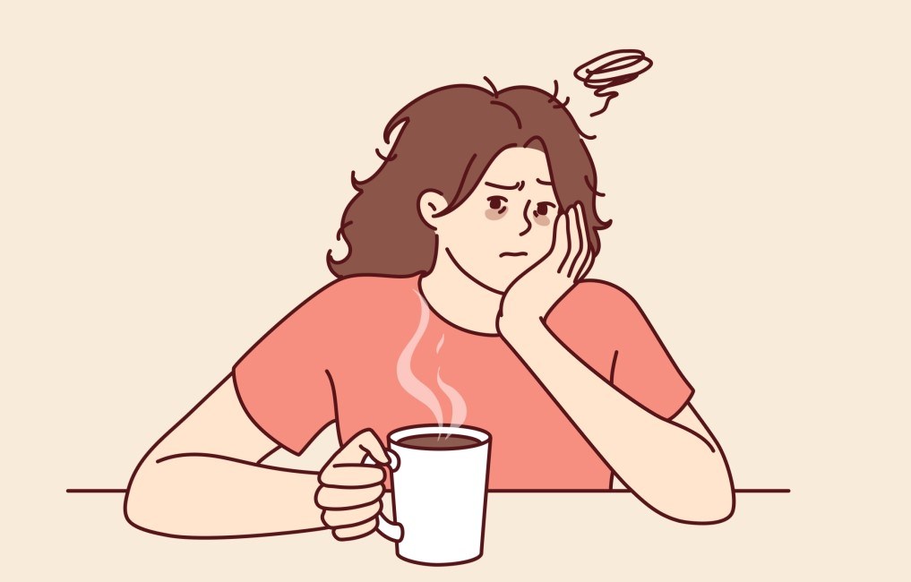 intoleranta la cafea. femeie cu durere de cap in timp ce bea cafea