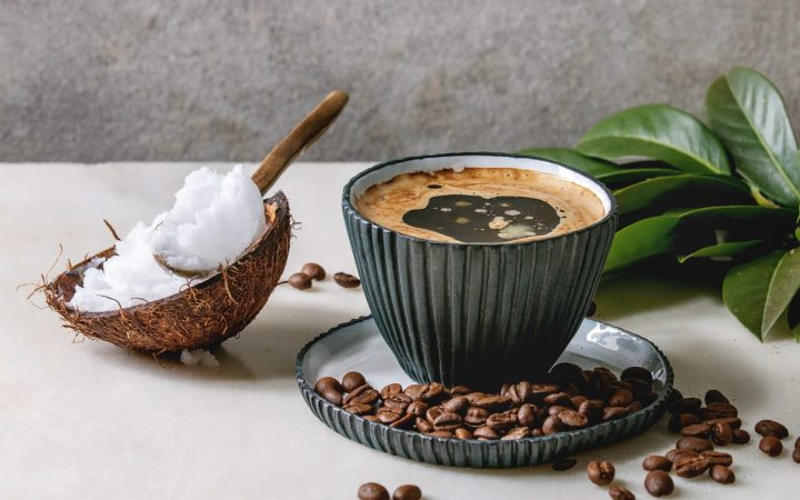 cafea alături de o jumătate de nucă de cocos cu unt/ulei de ccocos