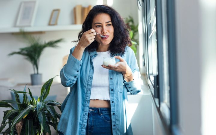 femeie fără grăsime pe abdomen cu bluză scurtă, care mănâncă iaurt