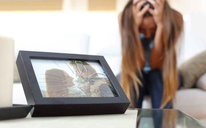 cum să treci peste o despărțire - femeie care plânge lângă o fotografie de cuplu spartă