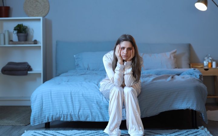 femeie pe marginea patului care nu poate să adoarmă noaptea - metode de a adormi mai repede