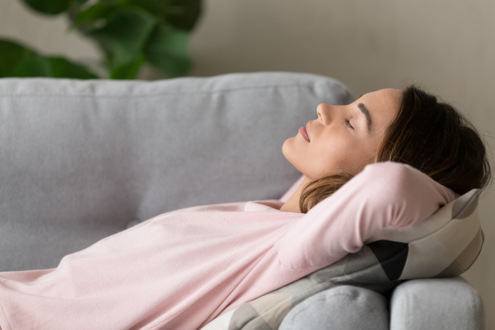 femeie care stă relaxată pe canapea, întinsă și cu ochii închiși