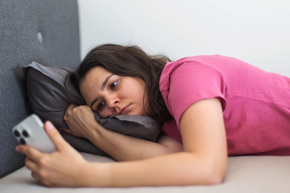 femeie care stă în pat și se uită pe telefon